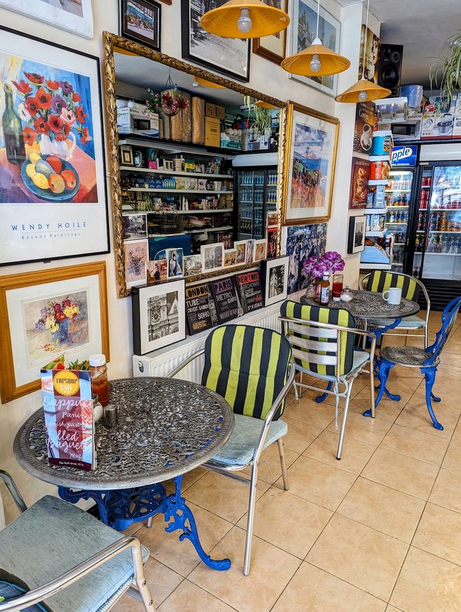 A marble bistro table with two mismatched metal chairs in a corner hung with framed prints