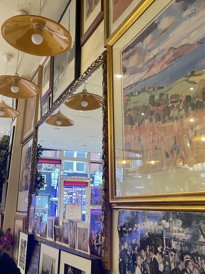 Pendant lamps, a large mirror and framed pictures crowding the wall above the front window