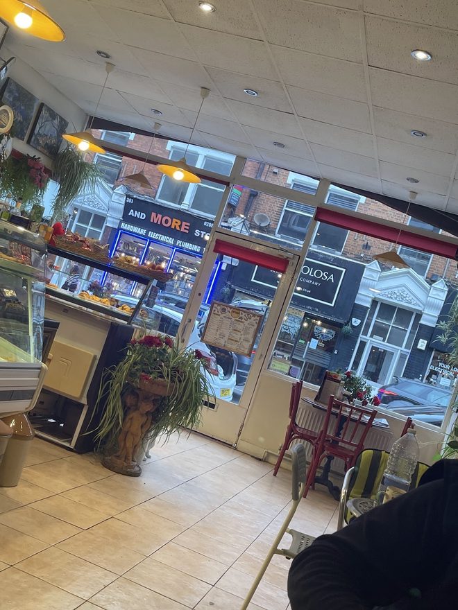 Looking out through the glass frontage onto the street, with a potted plant and a small table by the door