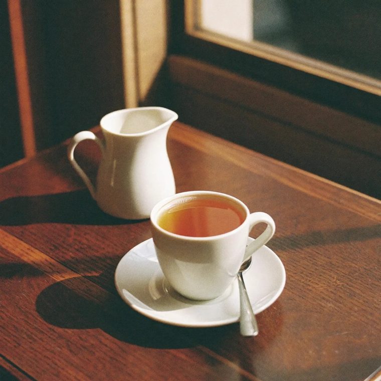 A mug of tea with a small milk jug on a wooden table